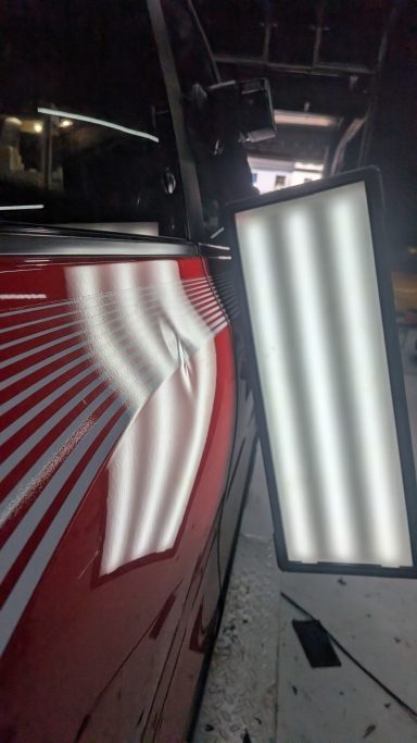 Roter Fahrzeugkörper mit einer Lichtquelle, die reflektierende Streifen zeigt.