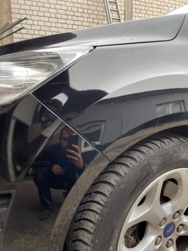 Schwarzes Auto mit reflektierender Karosserie und Sicht auf den Fotografen.
