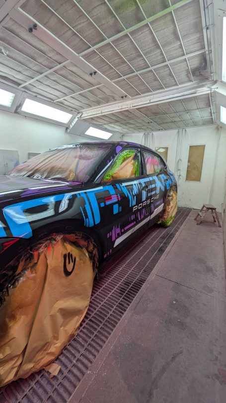 Auto mit bunten Graffiti und Schutzfolien in einer Lackierkabine.