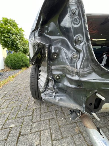 Beschädigte Karosserie eines Fahrzeugs mit deformiertem Heckbereich.